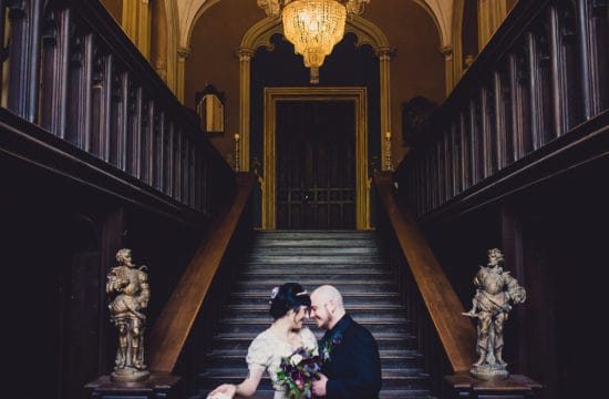 just married couple embracing in gothic castle bottom of stairs