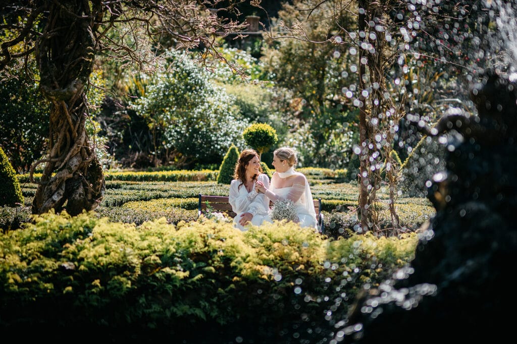 beautiful west Cork wedding ceremony at Bantry House brides sitting close together in bantry house garden 